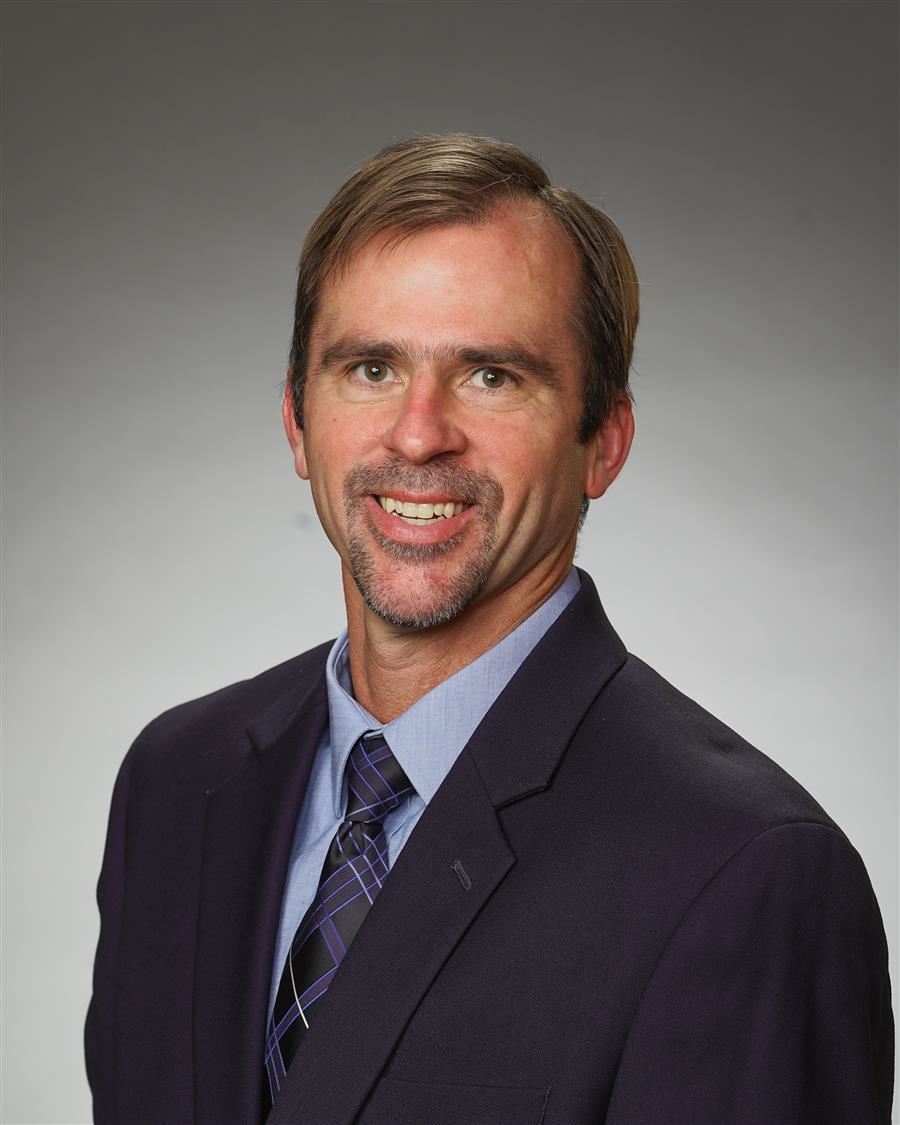  Donnie Lewellyn smiles to camera while wearing a suit.
